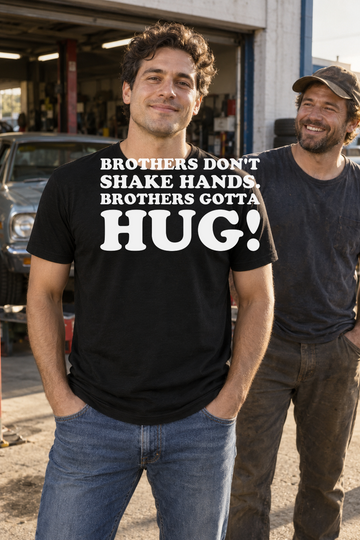 AI-generated lifestyle visualization: person wearing the black tri-blend Brothers Don't Shake Hands. Brothers Gotta Hug! quote T-shirt in a sunlit garage with a friend