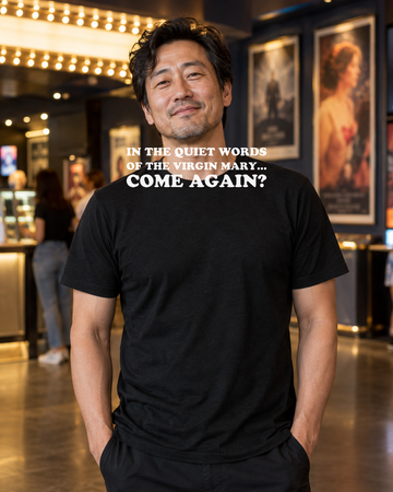 AI-generated lifestyle visualization of a person wearing the In the Quiet Words of the Virgin Mary... Come Again? black tri-blend quote T-shirt in an independent cinema lobby
