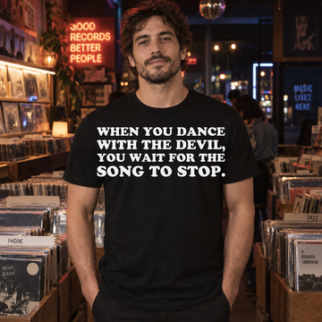 AI-generated lifestyle visualization of a person wearing the Dance with the Devil black quote T-shirt in an independent record shop