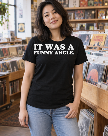 AI-generated lifestyle visualization of a person wearing the It Was a Funny Angle. black tri-blend quote T-shirt in an independent record shop