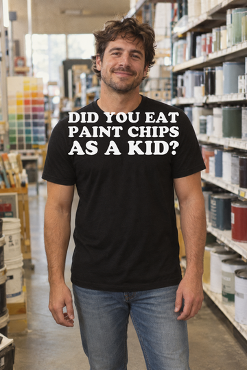 AI-generated lifestyle visualization: person wearing the black tri-blend Did You Eat Paint Chips as a Kid? quote T-shirt in a vintage paint store