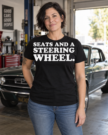 AI-generated lifestyle visualization of a person wearing the Seats and a Steering Wheel. black tri-blend quote T-shirt in a classic-car garage
