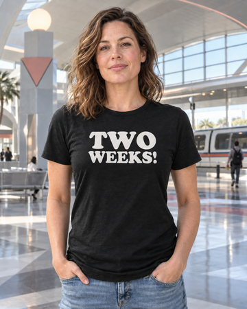 AI-generated lifestyle visualization of a woman wearing the black tri-blend Two Weeks quote T-shirt in a retro-futurist transit terminal