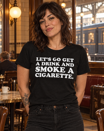 AI-generated lifestyle visualization: person wearing the black tri-blend Let's Go Get a Drink and Smoke a Cigarette. quote T-shirt in a vintage railway refreshment room with patterned tile, luggage racks, and amber evening light