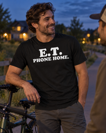 AI-generated lifestyle visualization: person wearing the black tri-blend E.T. Phone Home. quote T-shirt in a quiet suburban bike path at blue hour with warm house lights in the distance