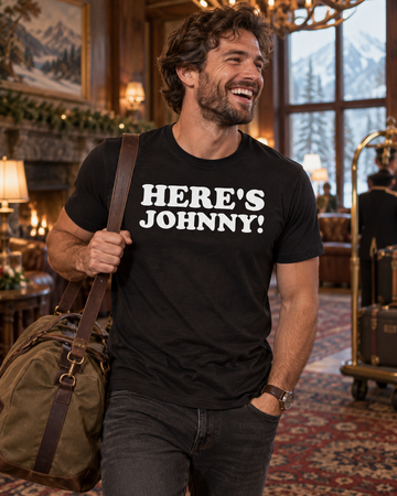 AI-generated lifestyle visualization: person wearing the black tri-blend Here's Johnny! quote T-shirt in a vintage mountain hotel lobby with patterned carpet and cold winter window light