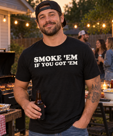 AI-generated lifestyle visualization: person wearing the black tri-blend Smoke 'Em If You Got 'Em quote T-shirt at a backyard cookout
