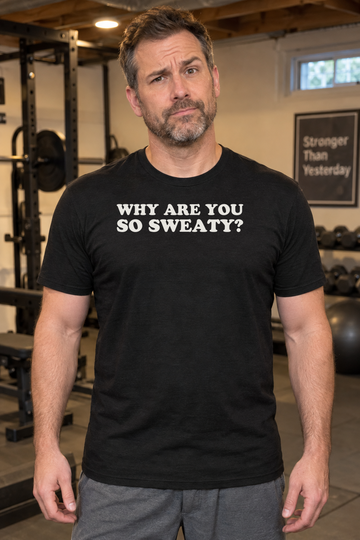 AI-generated lifestyle visualization: person wearing the black tri-blend Why Are You So Sweaty? quote T-shirt in suburban basement home gym with exercise equipment and warm practical lighting