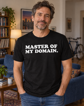 AI-generated lifestyle visualization: person wearing the black tri-blend Master of My Domain. quote T-shirt in classic 1990s apartment living room with a blue couch, bicycles blurred in the background, and no show-specific props