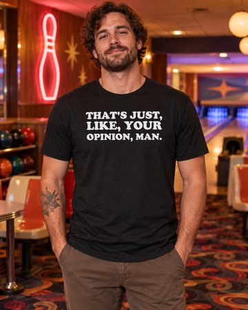 AI-generated lifestyle visualization: person wearing the black tri-blend That's Just, Like, Your Opinion, Man. quote T-shirt in a retro bowling alley lounge with patterned carpet, molded chairs, and warm neon spill