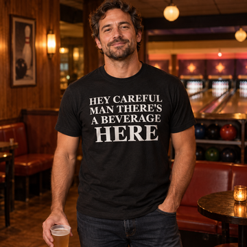 AI-generated lifestyle visualization: person wearing the black tri-blend Hey Careful Man There's a Beverage Here quote T-shirt in a neighborhood bowling lounge