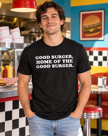 AI-generated lifestyle visualization: person wearing the black tri-blend Good Burger, Home of the Good Burger. quote T-shirt in a colorful independent burger counter with checkerboard tile, paper hats, and saturated 1990s color