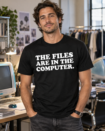AI-generated lifestyle visualization: person wearing the black tri-blend The Files Are in the Computer. quote T-shirt in early-2000s fashion-studio office with translucent desktop computers and no visible logos
