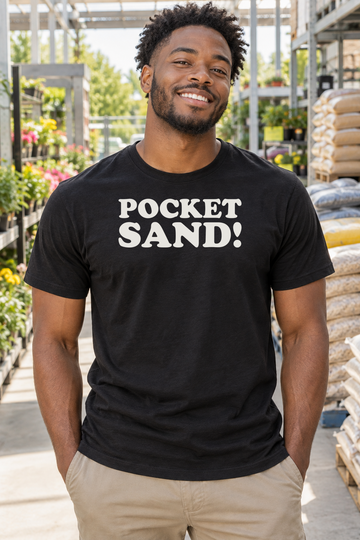 AI-generated lifestyle visualization: person wearing the black tri-blend Pocket Sand! quote T-shirt in sunny suburban hardware-store garden aisle with bags of sand and no visible brands