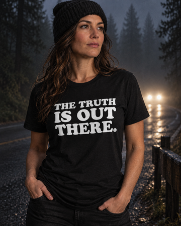 AI-generated lifestyle visualization: person wearing the black tri-blend The Truth Is Out There. quote T-shirt in misty pine-forest roadside at night with distant headlights and subtle analog-camera grain