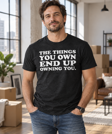 AI-generated lifestyle visualization: person wearing the black tri-blend The Things You Own End Up Owning You quote T-shirt while moving into a loft