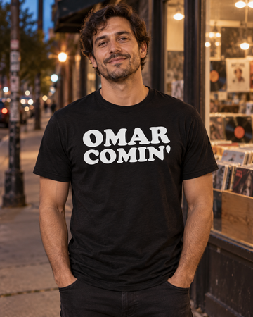 AI-generated lifestyle visualization: person wearing the black tri-blend Omar Comin' quote T-shirt outside an independent record shop