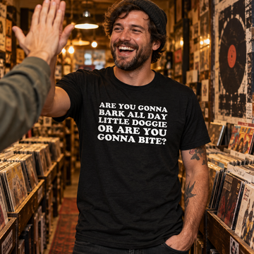 AI-generated lifestyle visualization: person wearing the black tri-blend Are You Gonna Bark All Day quote T-shirt while high-fiving a friend in a record store