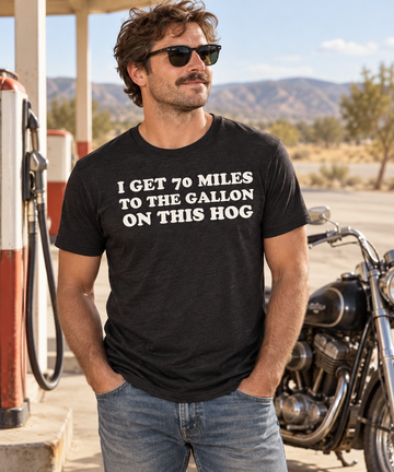 AI-generated lifestyle visualization: person wearing the black tri-blend I Get 70 Miles to the Gallon on This Hog quote T-shirt at a roadside gas station