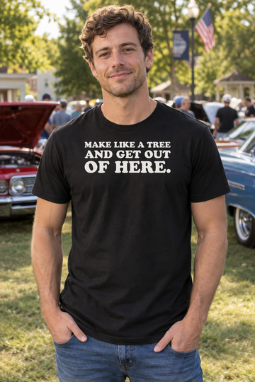 AI-generated lifestyle visualization: person wearing the black tri-blend Make Like a Tree and Get Out of Here. quote T-shirt in small-town park beside a vintage car show with no recognizable vehicle branding