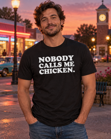AI-generated lifestyle visualization: person wearing the black tri-blend Nobody Calls Me Chicken. quote T-shirt in late-1980s suburban town square at dusk with neon storefront glow and no visible brands