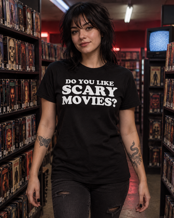 AI-generated lifestyle visualization: person wearing the black tri-blend Do You Like Scary Movies? quote T-shirt in an independent video store horror aisle at night with VHS cases, practical fluorescent light, and no branded posters