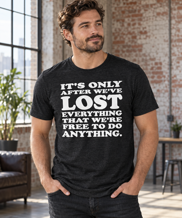 AI-generated lifestyle visualization: person wearing the black tri-blend It's Only After We've Lost Everything That We're Free to Do Anything quote T-shirt in a sparse warehouse loft