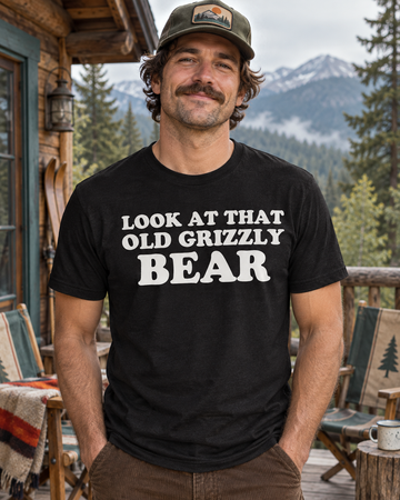 AI-generated lifestyle visualization: person wearing the black tri-blend Look at That Old Grizzly Bear quote T-shirt at a mountain lodge