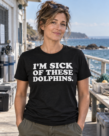 AI-generated lifestyle visualization: person wearing the black tri-blend I'm Sick of These Dolphins. quote T-shirt in a retro marine research station hallway with porthole windows and faded blue equipment