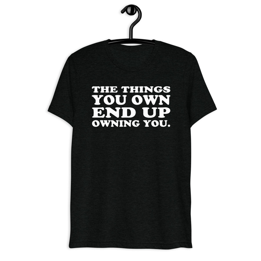 Front hanger mockup of the black tri-blend The Things You Own End Up Owning You quote T-shirt