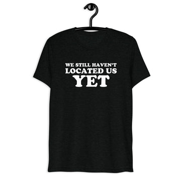 Front hanger view of black tri-blend quote shirt reading We Still Haven't Located Us Yet